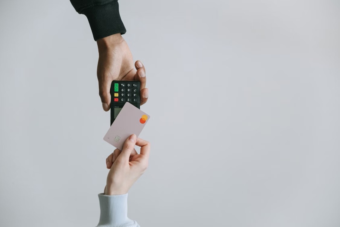 Hand die een bankkaart aan een betaalterminal geeft