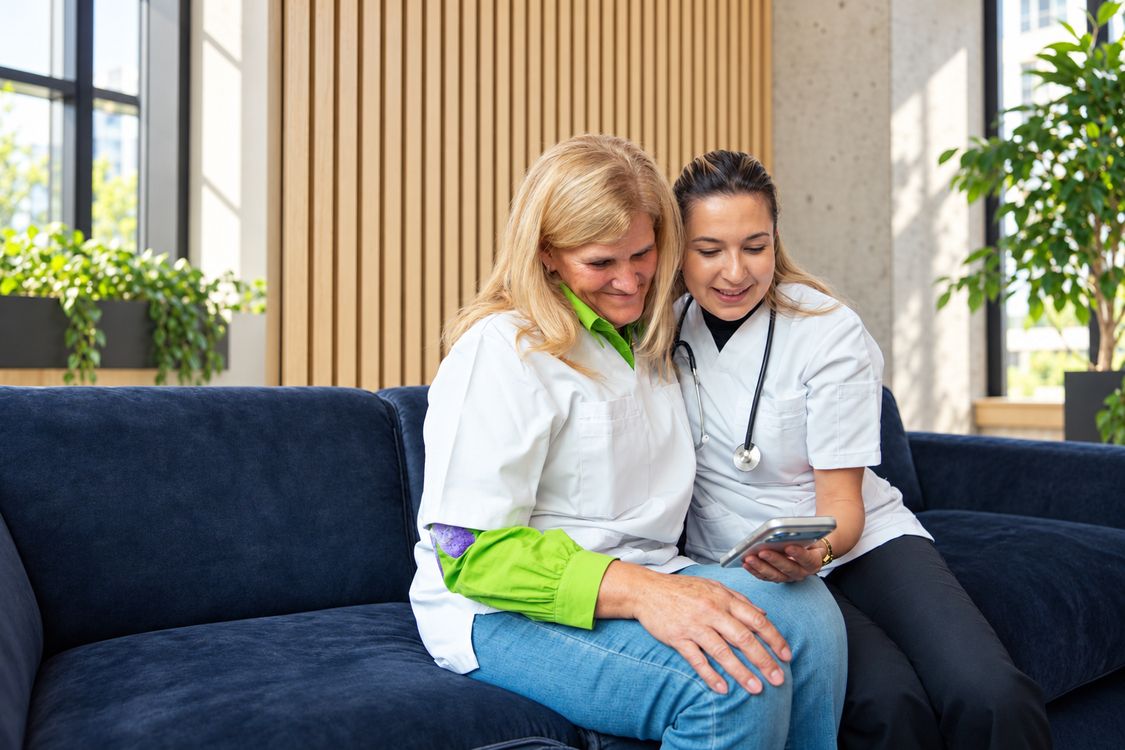 Nurse discussing a tablet with a colleague on a sofa