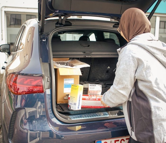 Verpleegkundige die medisch materiaal in een auto laadt